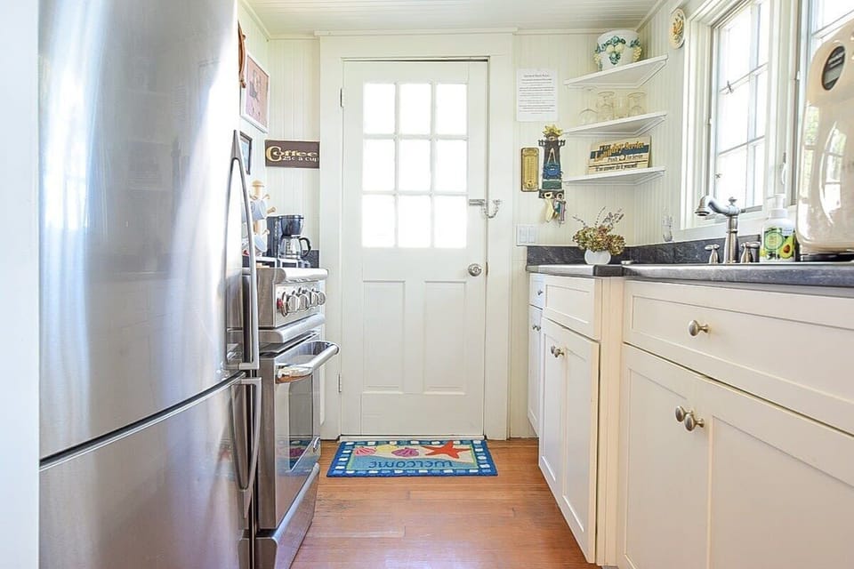 kitchen with white cabinets and stainless steel appliances leading to back door