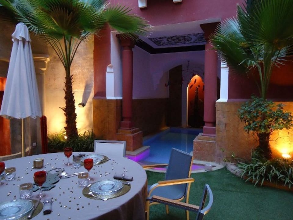 Romantic dinner table set at poolside within courtyard.