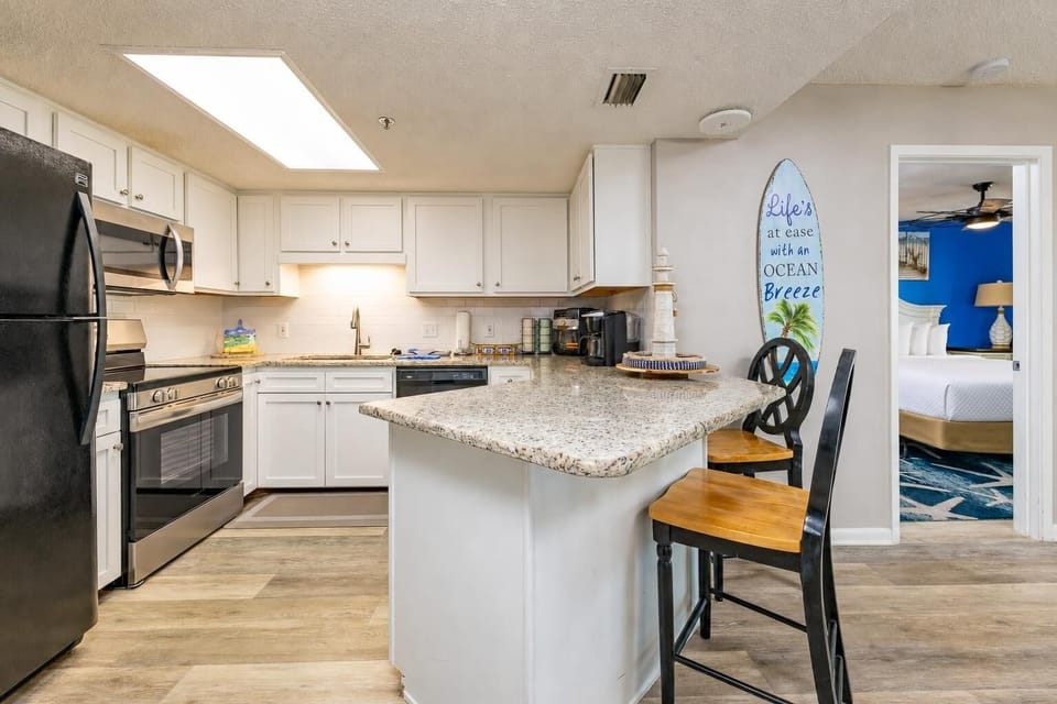 Kitchen with sleek black appliances, granite countertops, breakfast bar, and coffee station with Keurig and coffee maker