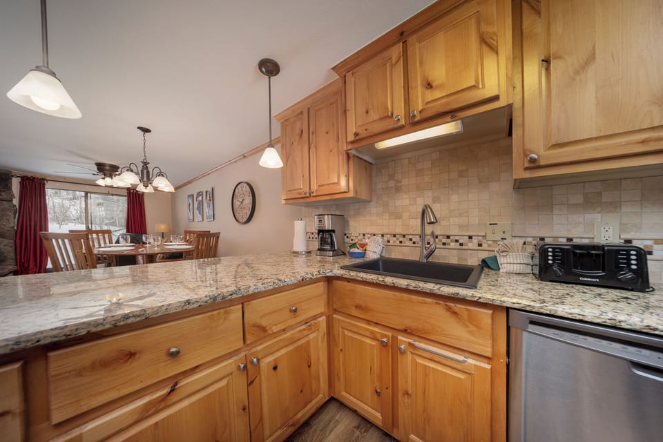 Your fully equipped kitchen features granite counters, stainless appliances, and warm wood cabinetry, perfect for preparing meals while enjoying mountain views.
