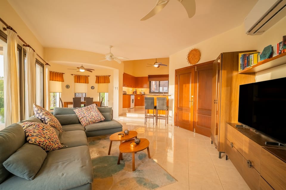 View of the living room with the dining area and the large open-plan kitchen visible in the background.