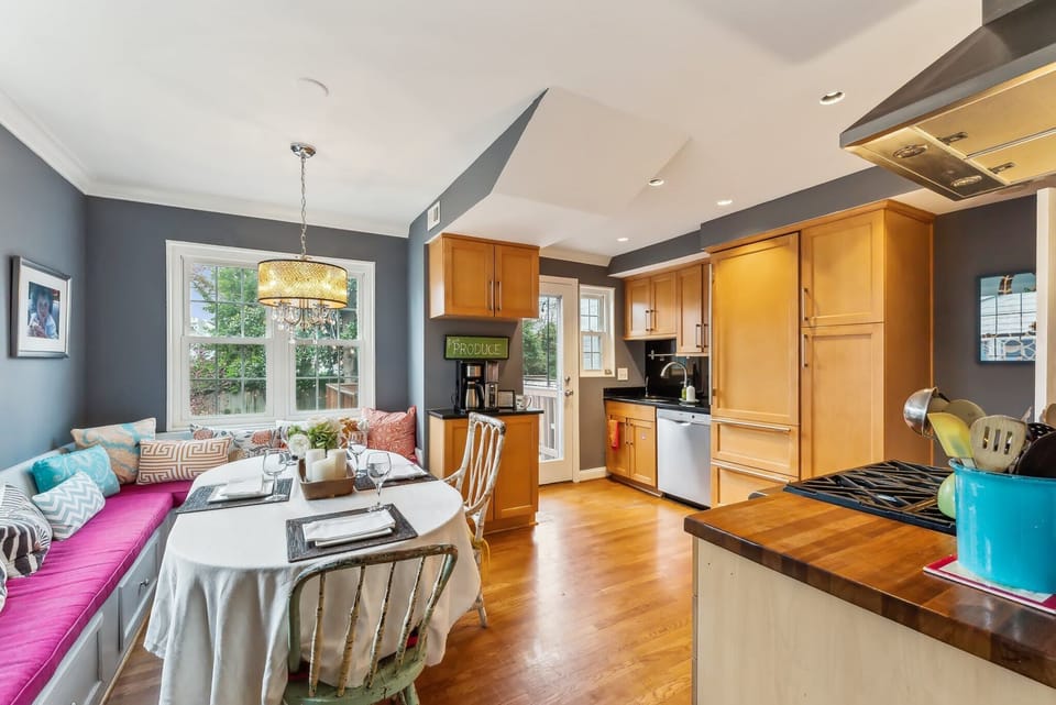 Wide open kitchen with comfortable bench seating and door to deck and garden/patio below.