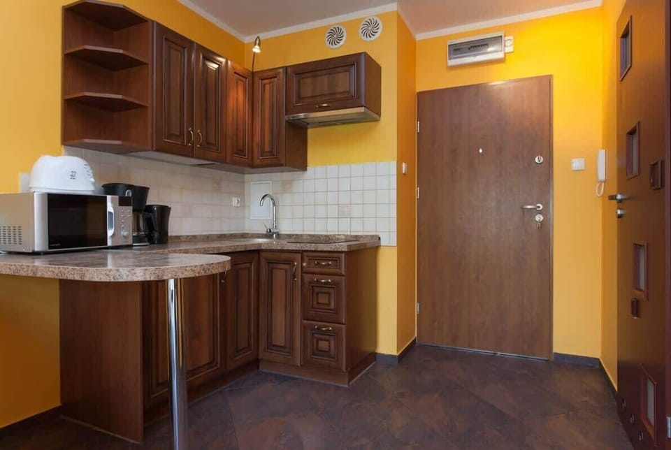 A closer view of the kitchen, with dark wooden cabinets and granite countertops. The kitchen includes basic appliances, offering a functional cooking space.