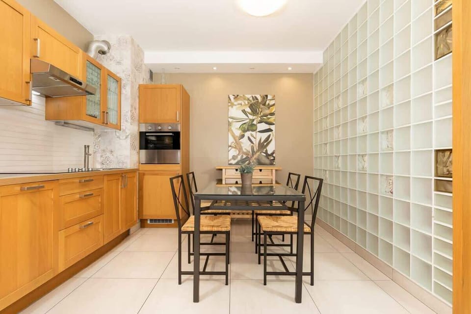 An open kitchen and dining space with light wood cabinets, a small table set for four, and an overall modern feel with good lighting.