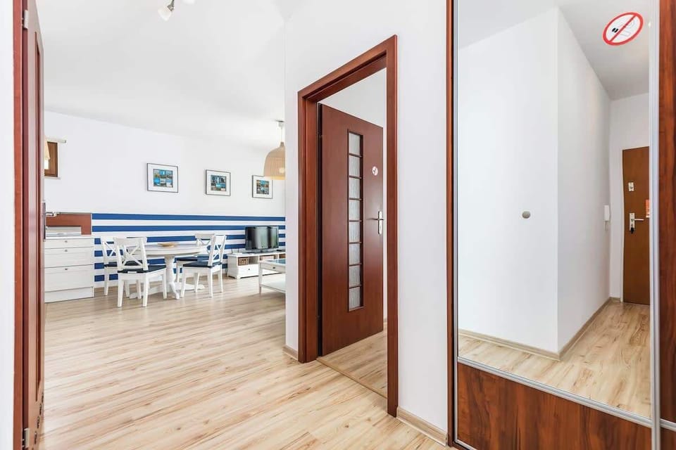 A view of the open-plan space, where the passage from the hallway to the living room can be seen. The dining table is in the background and the open kitchen is visible on the left.