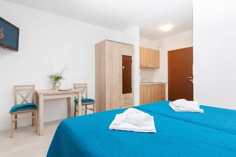  Another angle of the room, showing the bed and a small workspace with a wooden desk and chair. The room is bright, and the furnishings are simple, matching the overall aesthetic.