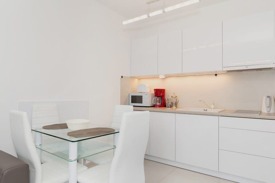 White and elegant kitchenette with a microwave, an electric kettle, a toaster, and a coffee machine.
