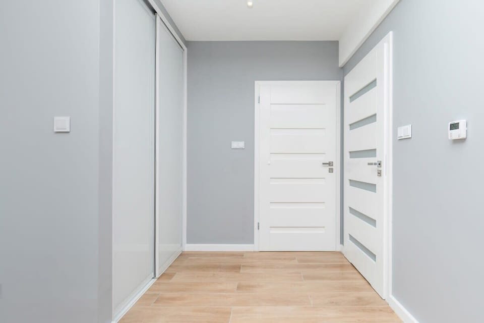 A simple hallway with wooden flooring, white walls, creating a peaceful transition area.