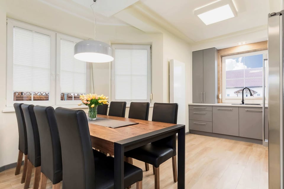 A dining area connected to a living room, featuring a wooden table with four chairs and an open, spacious design.