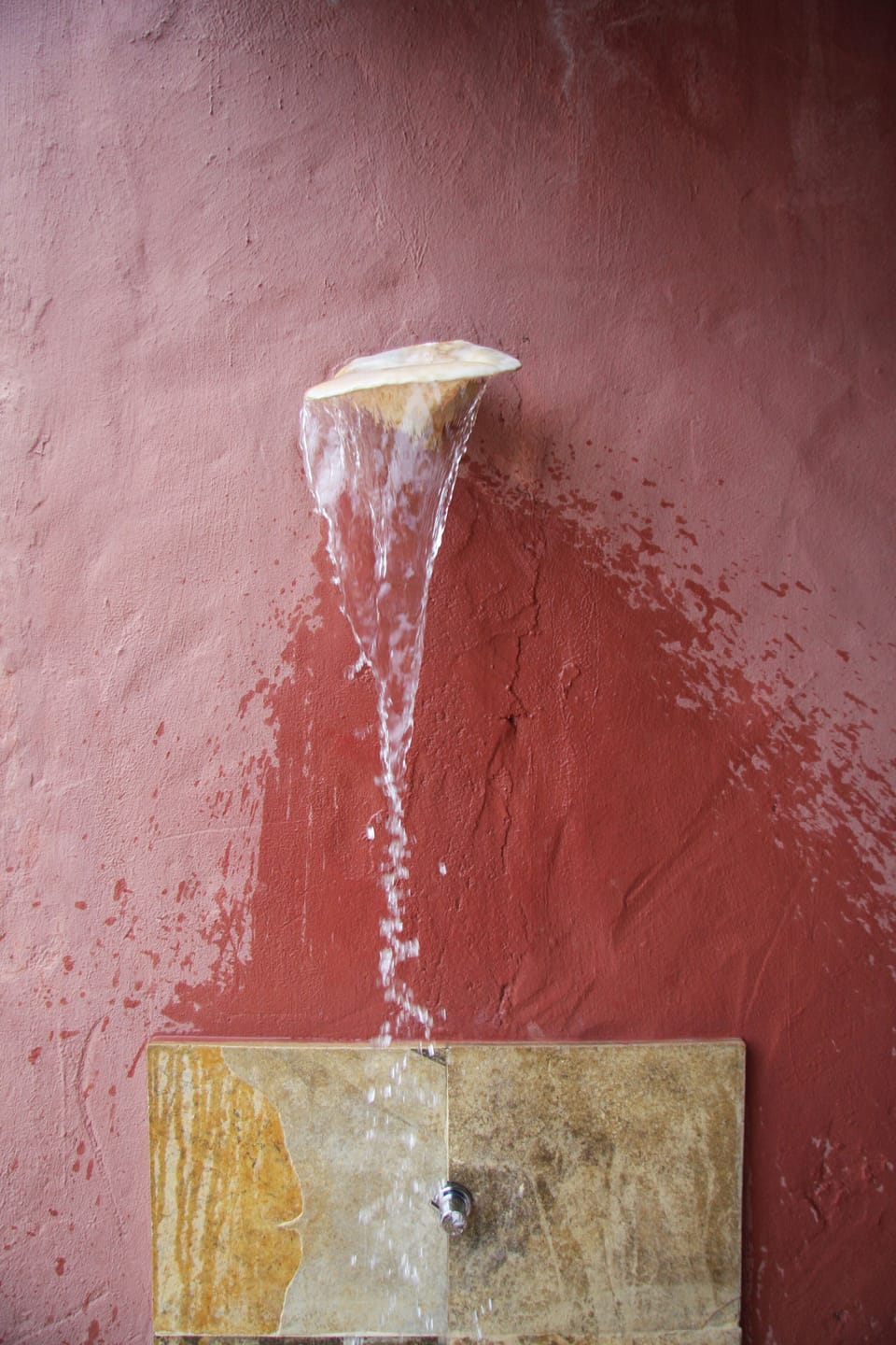 Outdoor shower with the water coming out from a giant sea shell.