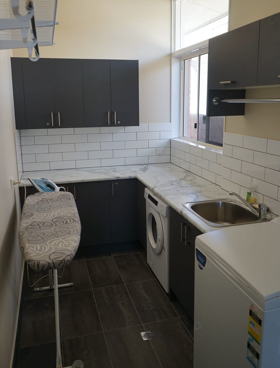 Separate laundry room with washer, dryer, tub & ironing facilities