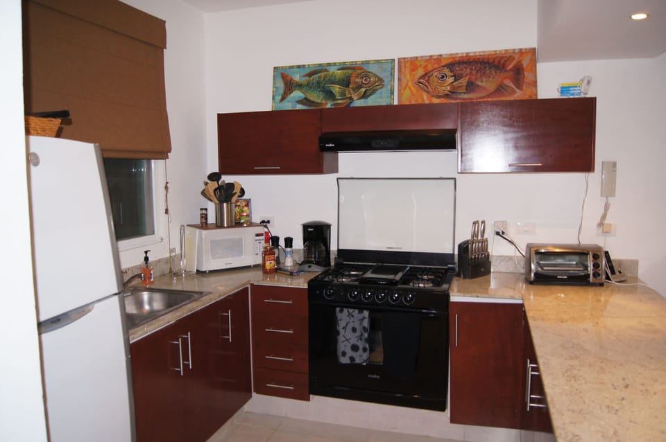 Kitchen with gas  stove, toaster, microwave, coffee maker, fridge.