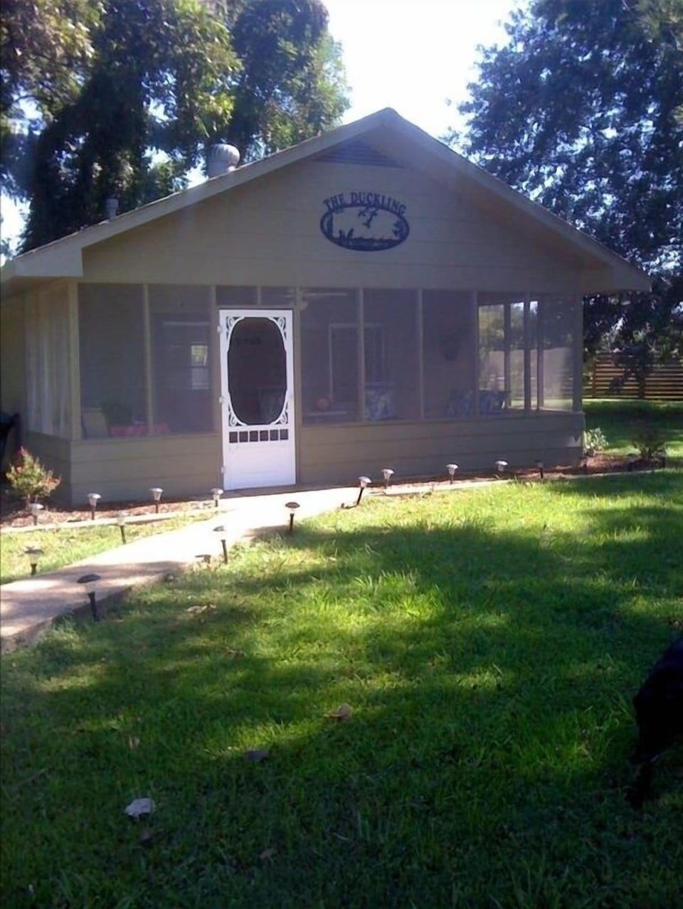 Screened porch with swing and two rocking chairs and a table and chairs.