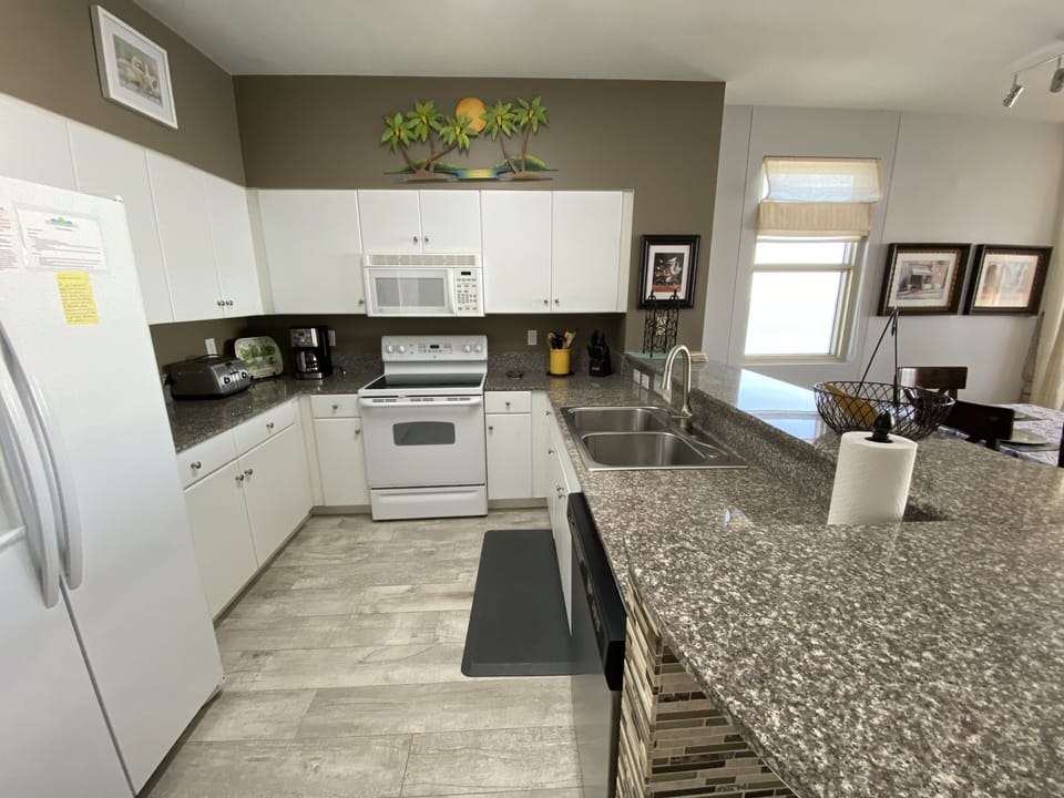 Fully stocked Kitchen features granite countertops and tiled bar.