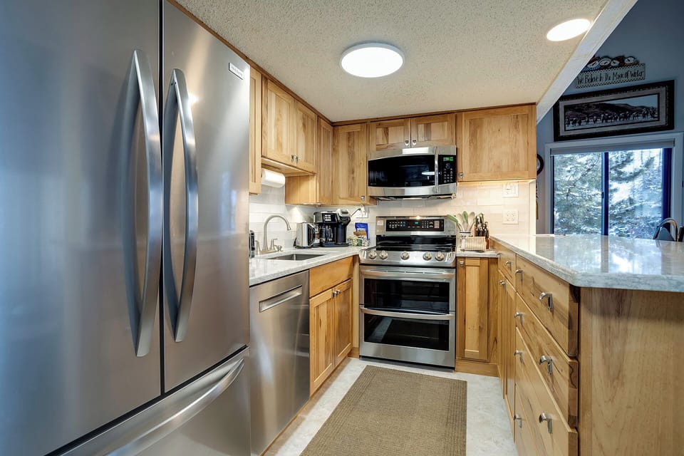 Your fully-equipped kitchen features warm wood cabinetry, granite countertops, and stainless steel appliances for all your culinary needs.