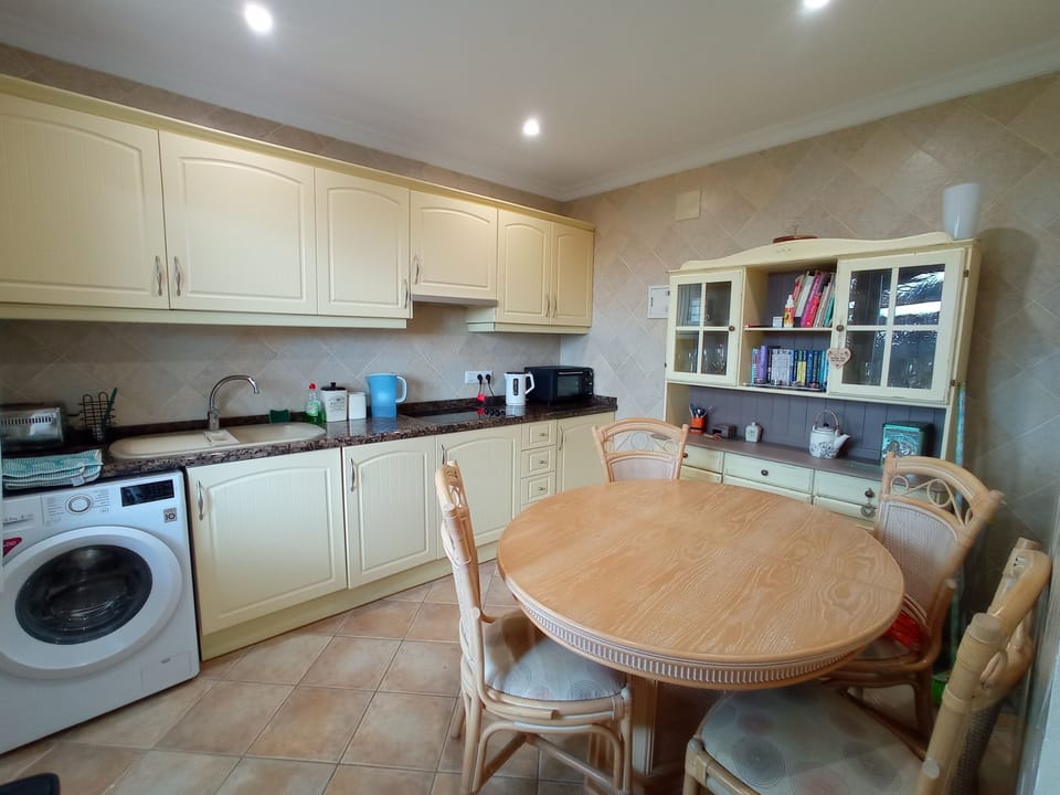 Utility room with additional washing machine, sink and dining table.