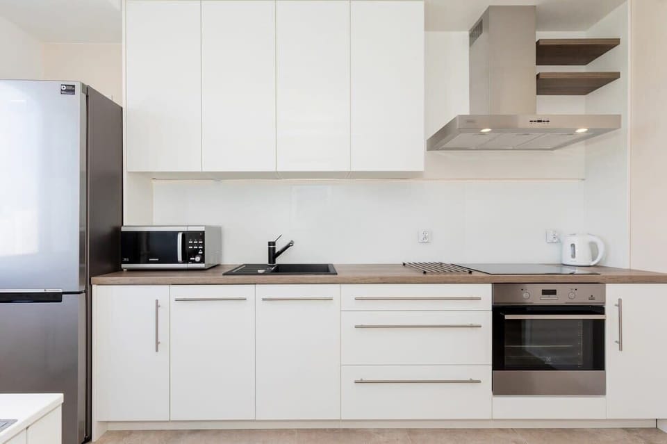A kitchenette with sleek white cabinets, built-in appliances, and a clean, minimalist design for easy cooking and meal prep.