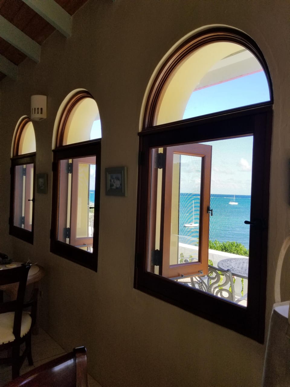 View from living room screened windows overlooking front deck, pool, sea + beach