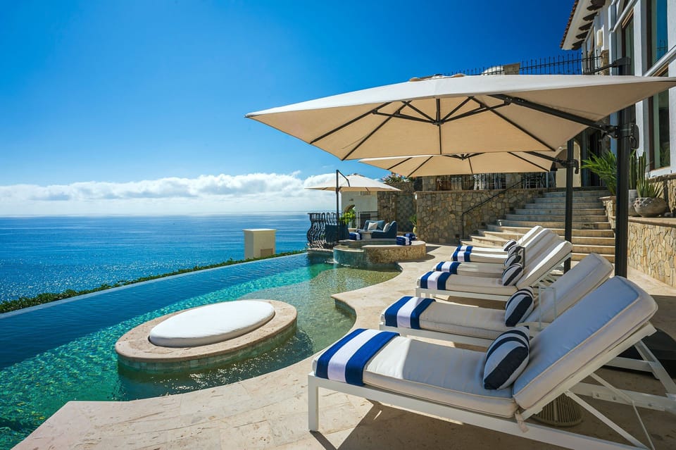 Sun loungers by the infinity pool and jacuzzi with ocean views at Casa Rio de Luna, Los Cabos.