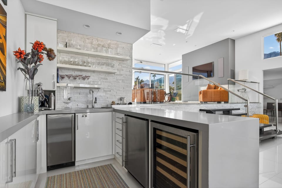 Lounge bar with ice maker, mini fridge, and wine cooler with plenty of glassware