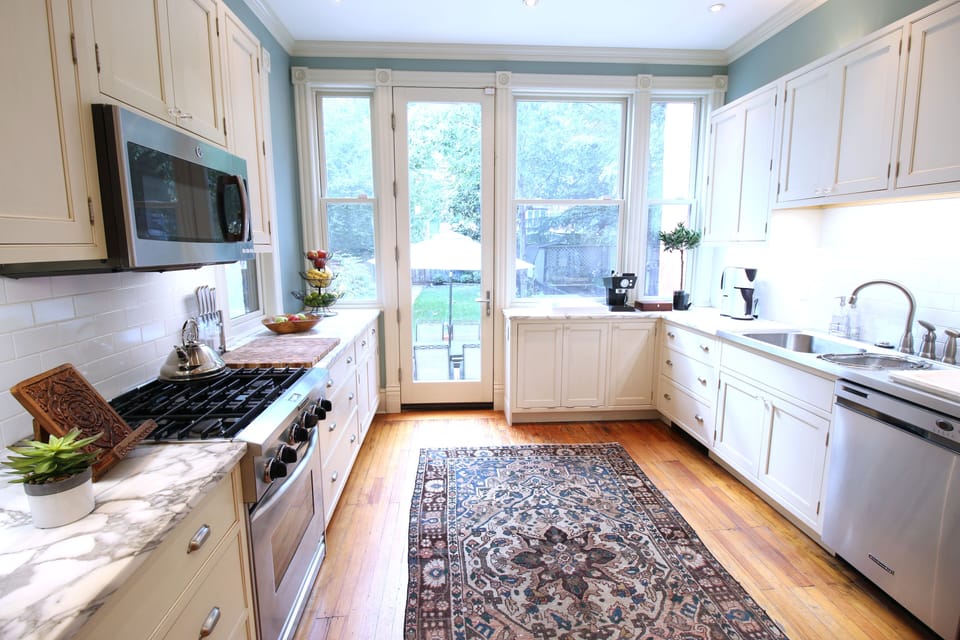 Large, sunny kitchen. Glass door opens to fenced, garden.