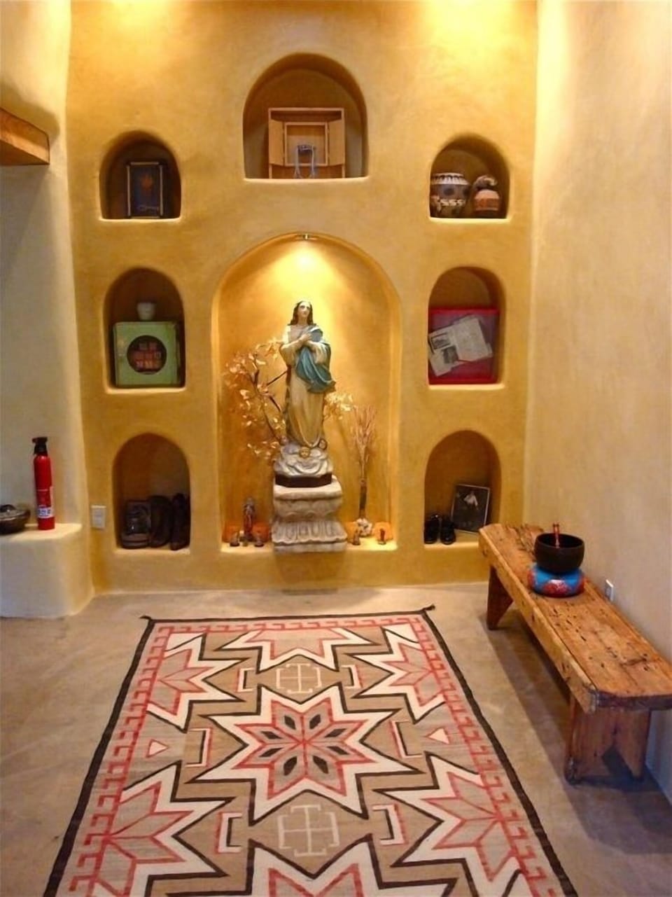 Entry with antique statuary, memorabilia and vintage rug.