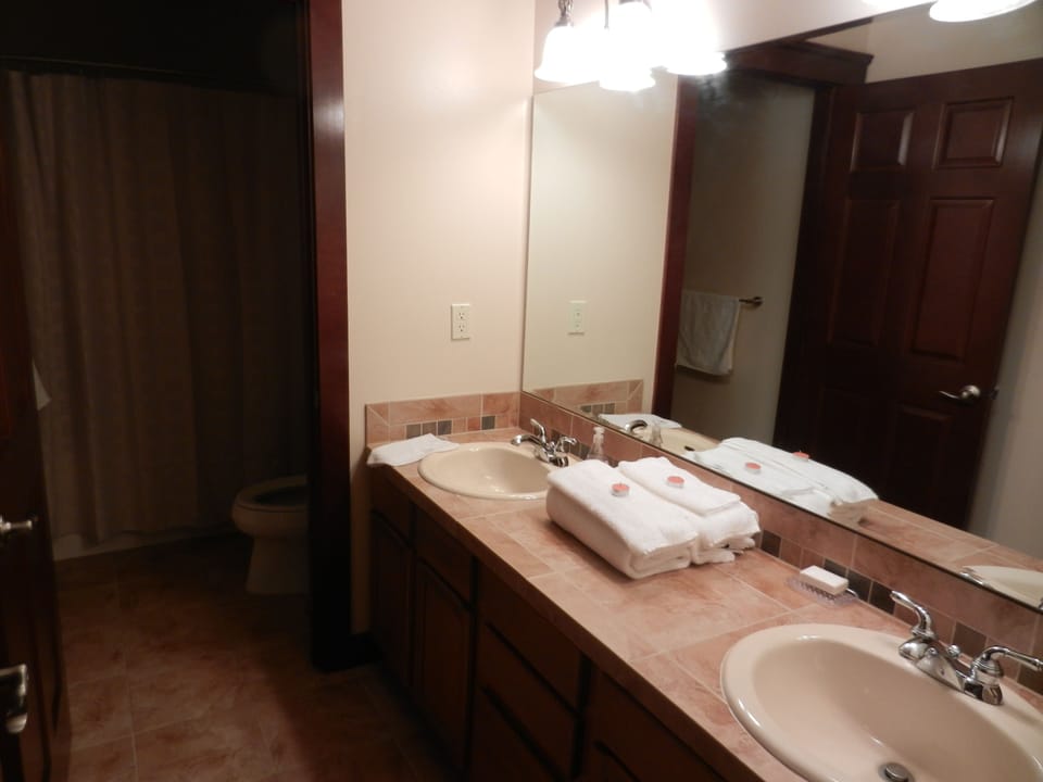 Upstairs bathroom with 2 sinks and a tub with shower and toilet.