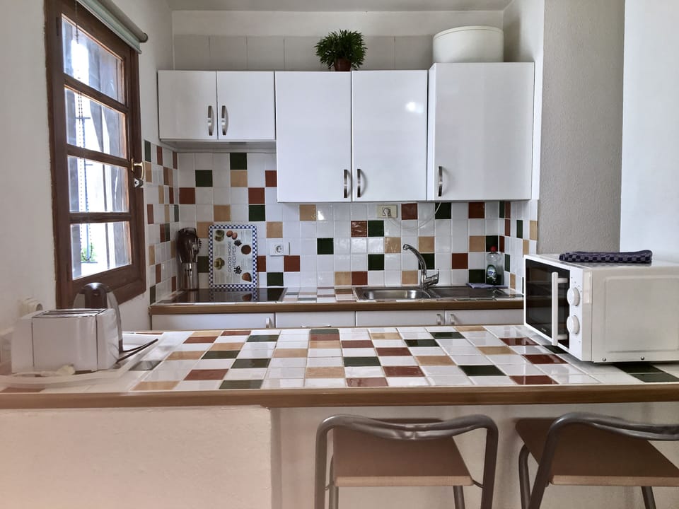 Fully tiled kitchenette with fridge, electric hob, kettle, toaster, microwave et