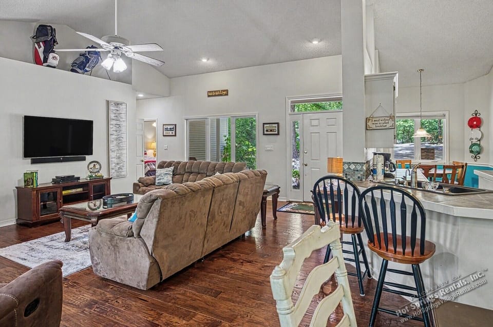 Stretch out in your open-concept living space, where rich wood floors flow from cozy living area to kitchen. Natural light pours through glass doors, inviting relaxation and connection.
