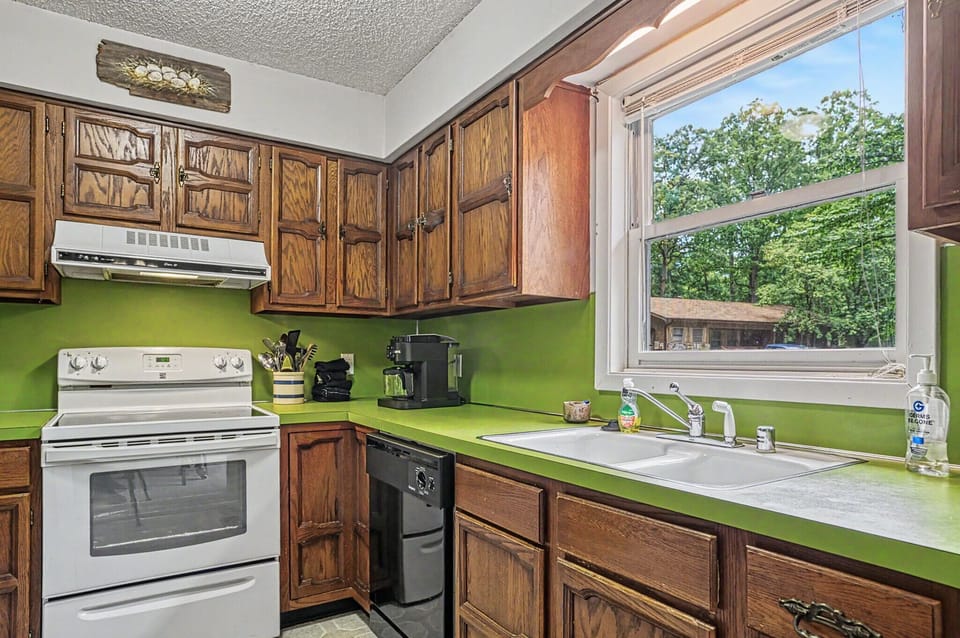 Prepare your favorite meals in this fully equipped kitchen, where natural light streams through the window and lush woodland views create a peaceful cooking experience.