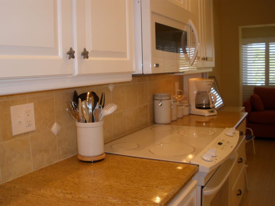 View of kitchen with granite counter, cabinets and stove