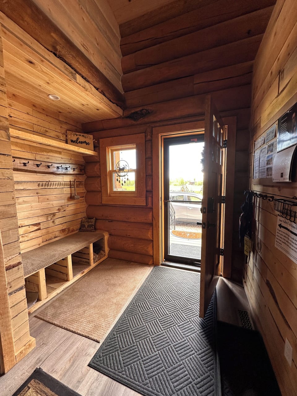 Entryway has coat hooks and a seating area with cubbies.