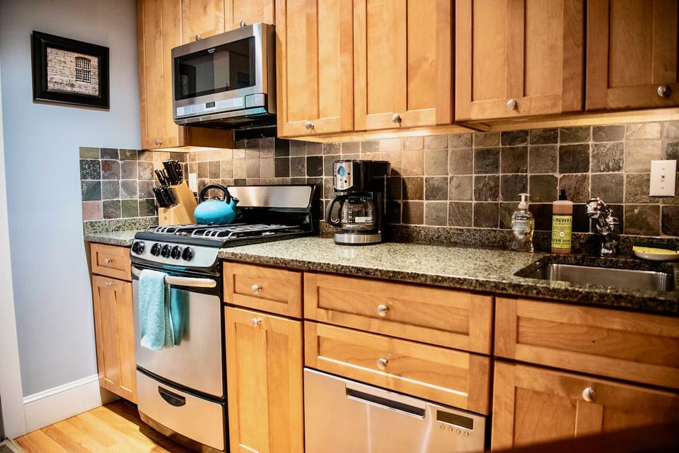 Fully stocked kitchen with stainless steel appliances, granite countertop.