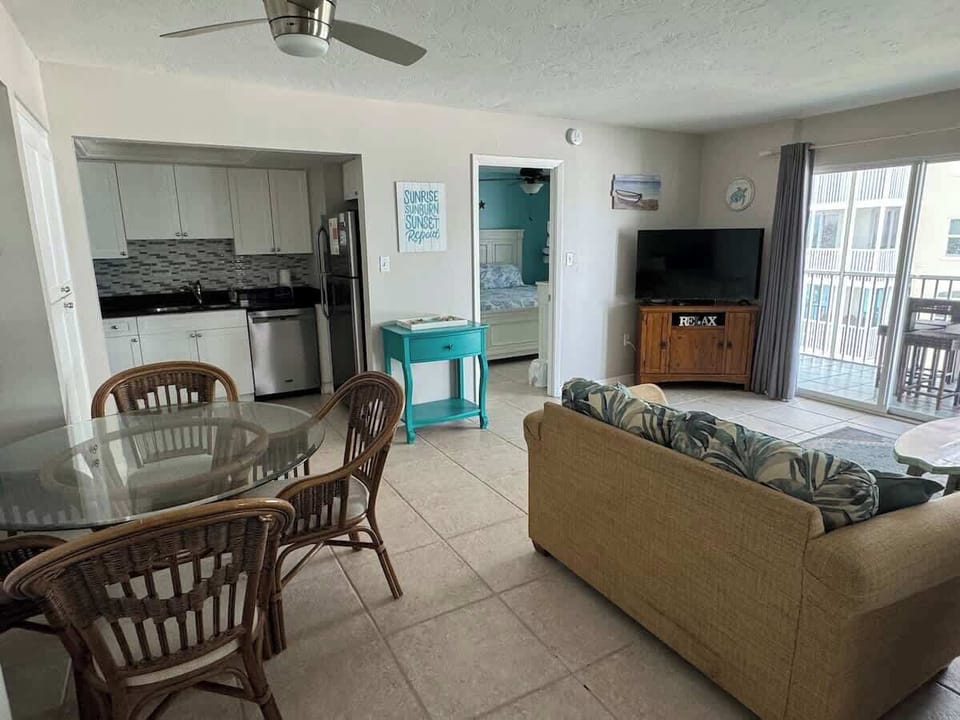 Cozy, open living room with leather sofa and chair. Opens directly to lanai.