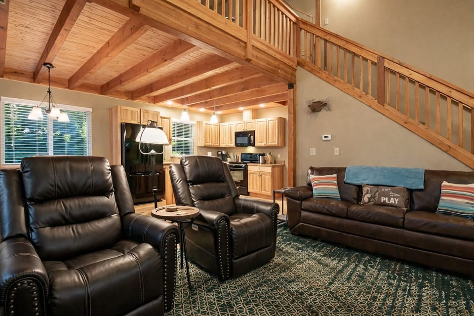 Sink into plush leather recliners under stunning exposed beams while your open kitchen awaits your culinary adventures in this inviting retreat.