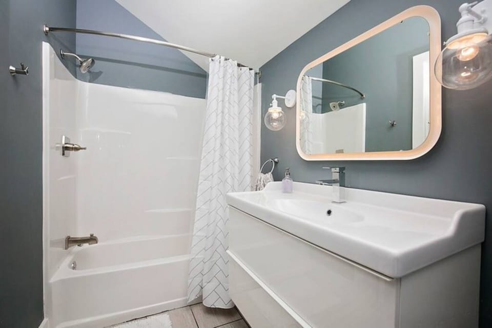 Bright and stylish bathroom with a full tub, glowing vanity, and sleek finishes.