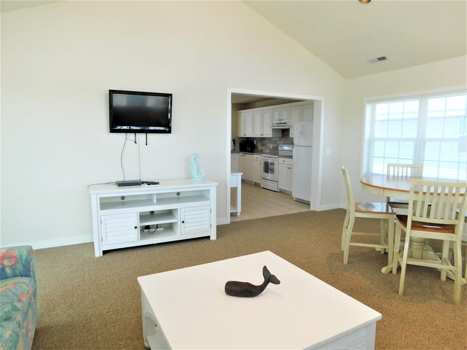 7 South Carolina Avenue - Dining and Lounge View - Alternate angle showing the dining set, media console with a mounted TV, and transition into the kitchen area.