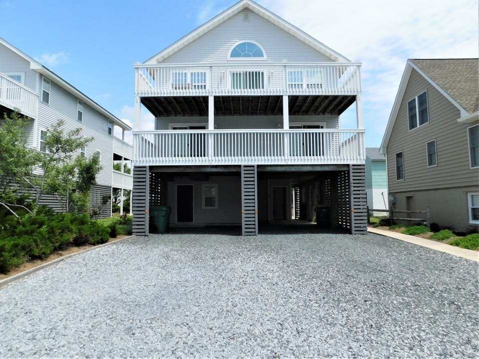 7 South Carolina Avenue - Front Exterior and Driveway - A direct frontal view of the property with a gravel driveway, highlighting the carports and the main entrance facade.