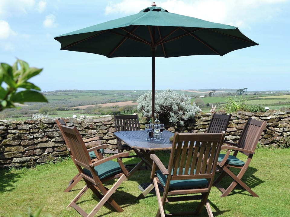 A large table with chairs is placed in an ideal location to take advantage of the sunshine and the view | Coachmans Cottage, White Cross, near Newquay