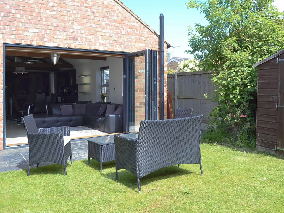 Bi-fold doors opening onto a flagged patio with seating area | The Old Stables, South Cave, near Beverley