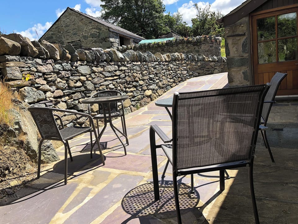 Paved patio with table and chairs | Ysgubor - Chwarel Goch Cottages, Tregarth, near Bangor