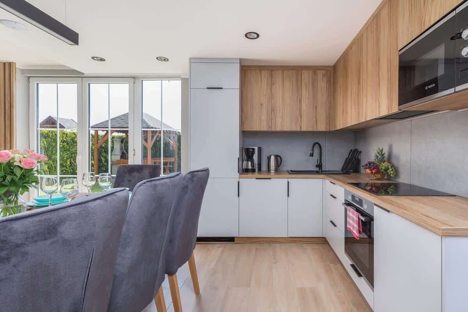 A bright kitchen-dining space with a modern wooden dining table set with turquoise plates and glasses, perfect for a family meal.