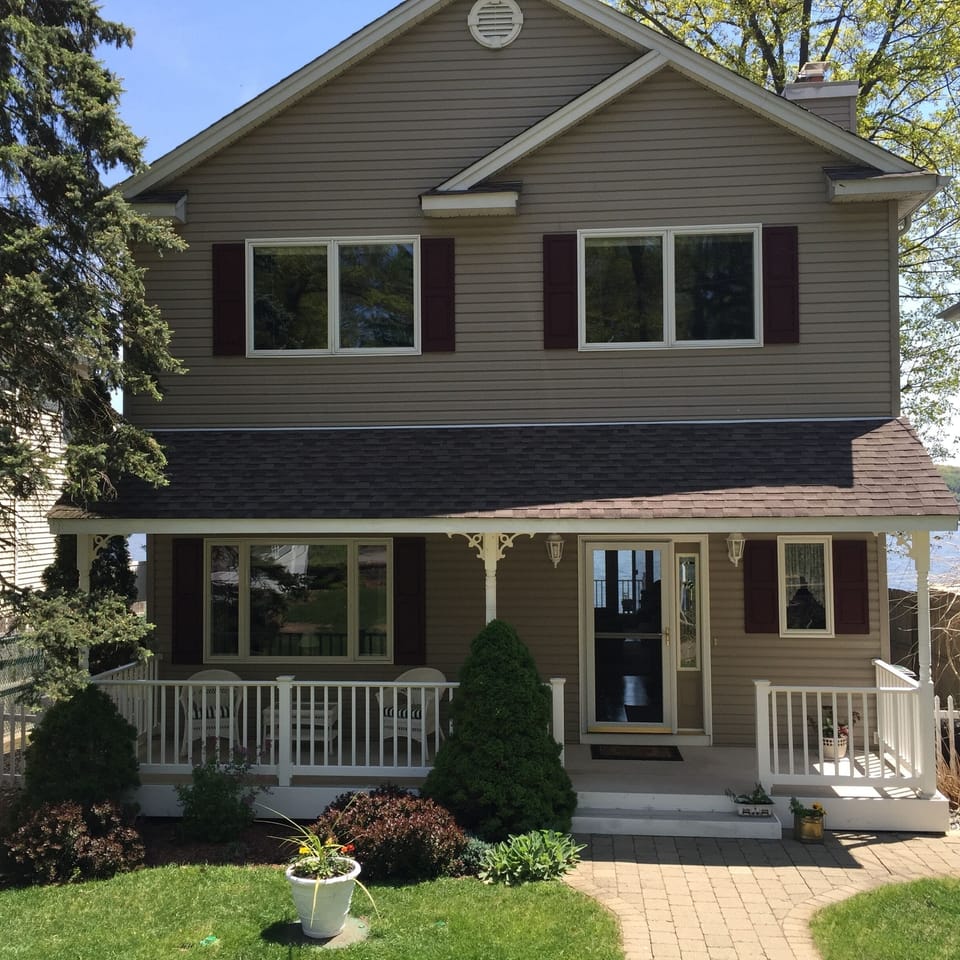 Front of home features covered porch and surrounded by beautiful garden