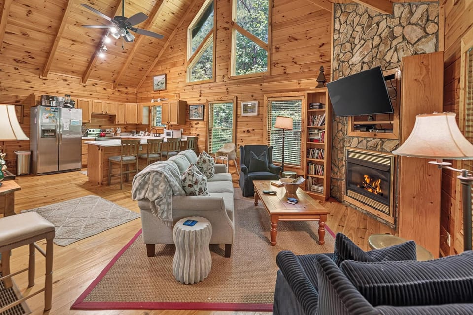 Cozy cabin living area with a stone fireplace and open kitchen, perfect for relaxing evenings.