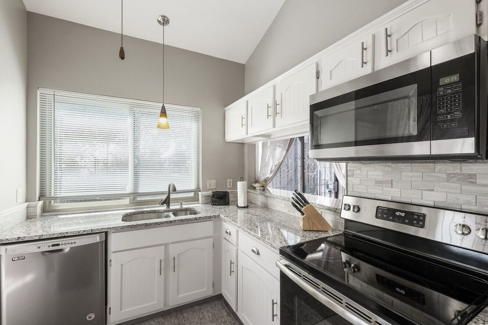 Sunlit granite kitchen with cathedral ceilings and new stainless appliances. 