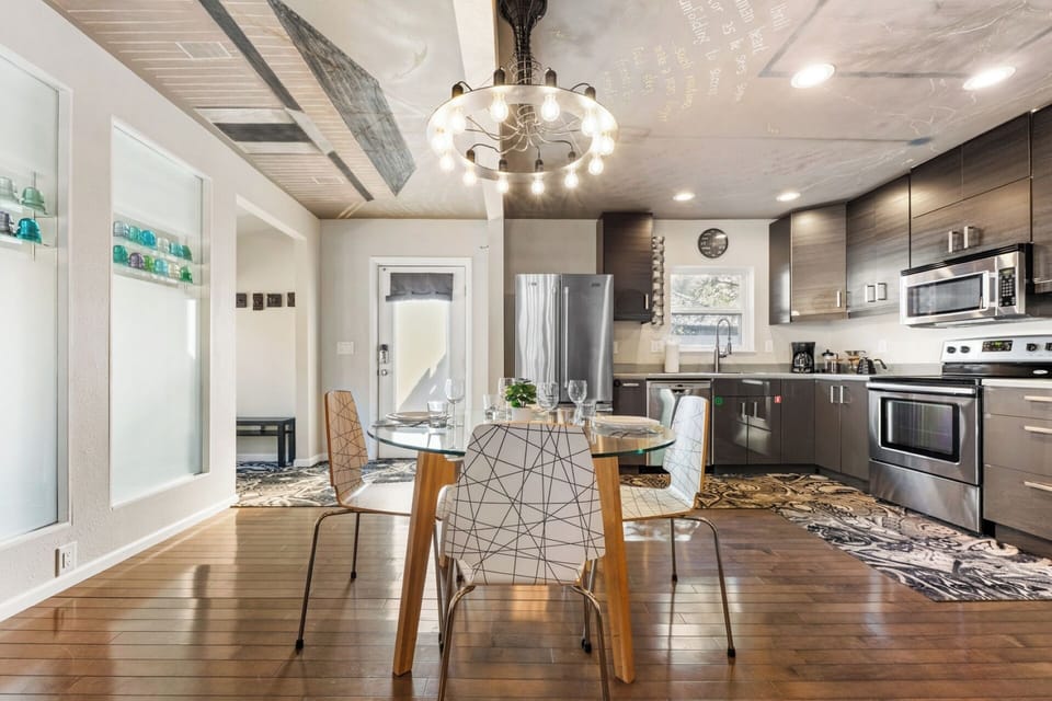 Dining area with glass & wood table, modern seating, Nikola Tesla ceiling mural