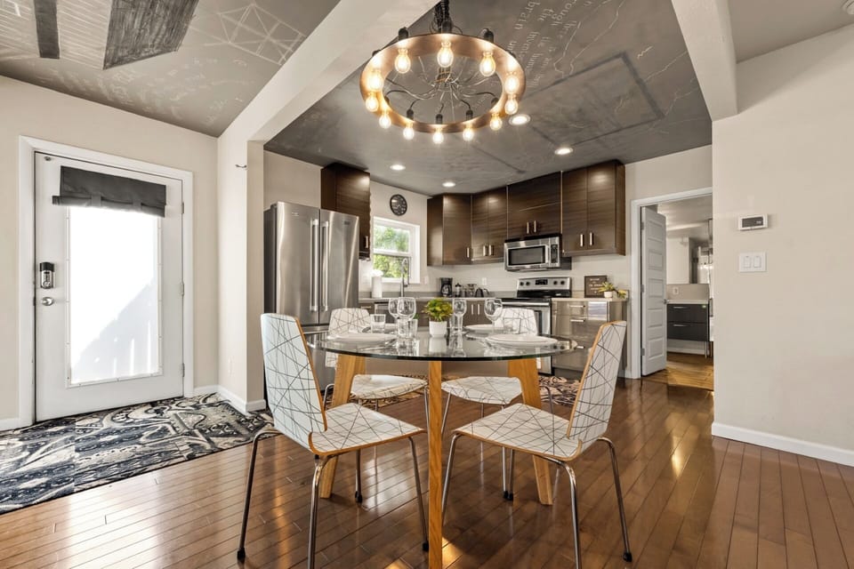 Dining area with glass & wood table, modern seating, Nikola Tesla ceiling mural