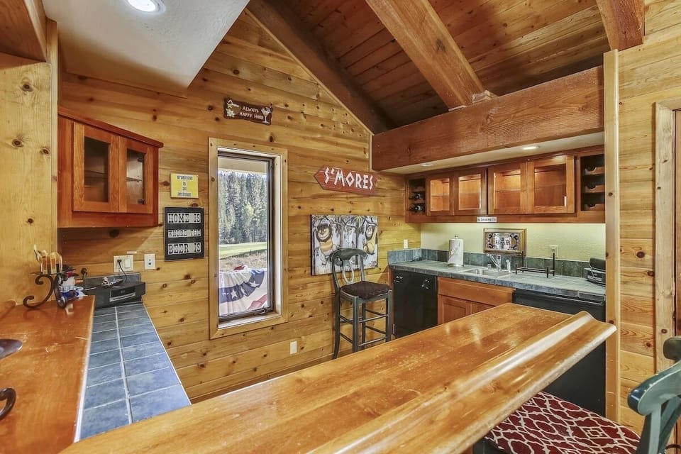 Cozy mountain style bar with wood finishes, sink, dishwasher, and glassware