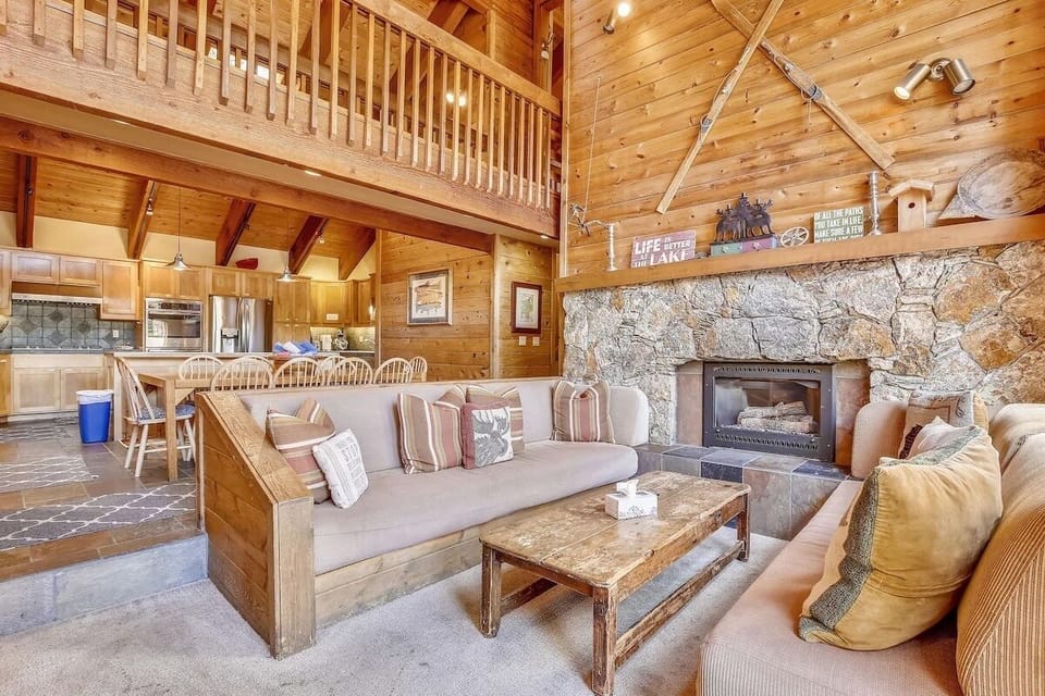 Spacious great room with vaulted ceilings, stone fireplace, and open kitchen.