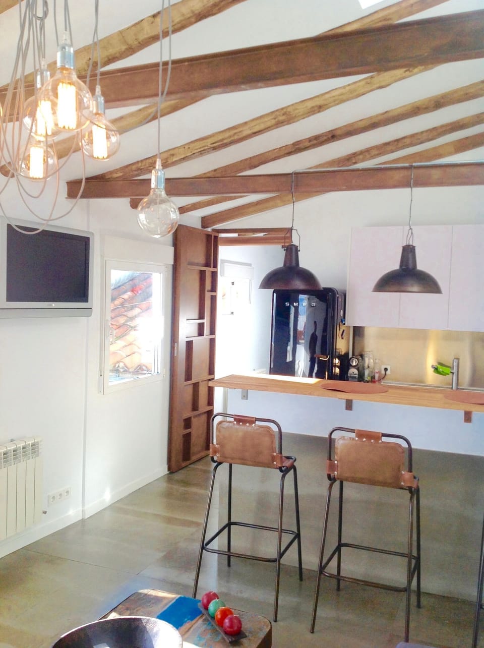 Wood and iron beams, metallic sculpted door, iron and leather bar chairs, Tv. 